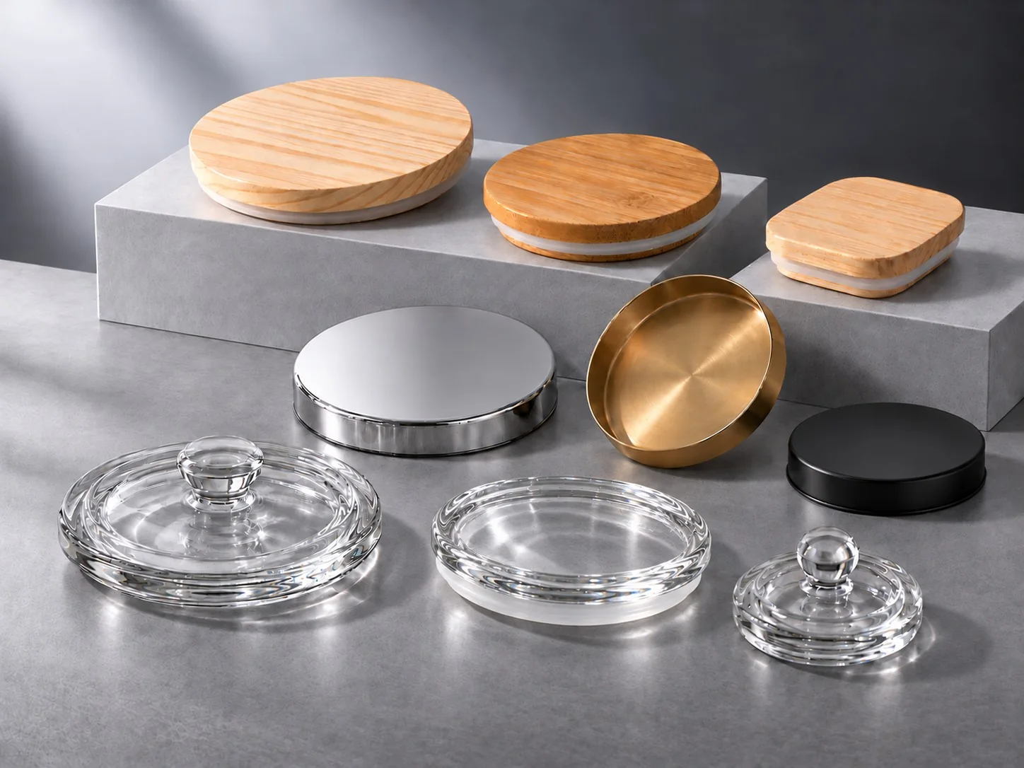 Wood, metal and glass lids in different sizes displayed on cool gray platforms